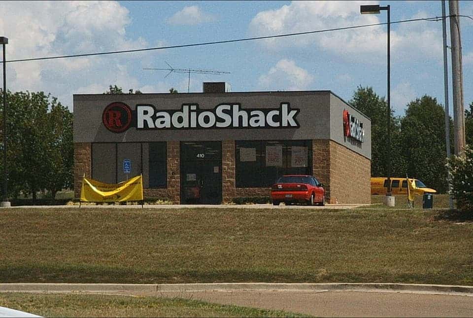 A small free-standing RadioShack store with the circle-R sign, seen from across a lawn